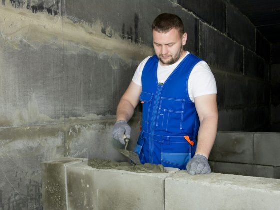 a man in blue overalls working on cement