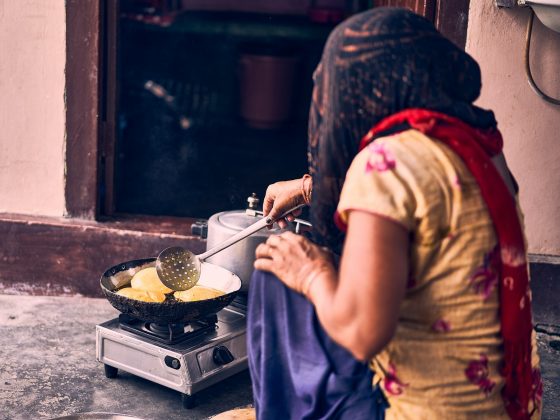 woman in brown shirt holding stainless steel cooking pot